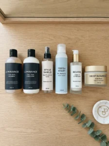 Flat lay of color-safe shampoo, conditioner, heat protectant spray, dry shampoo, leave-in conditioner, and hair mask on a clean vanity.