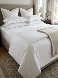 Hotel bed finishing details including hospital corners and smooth bedding.
