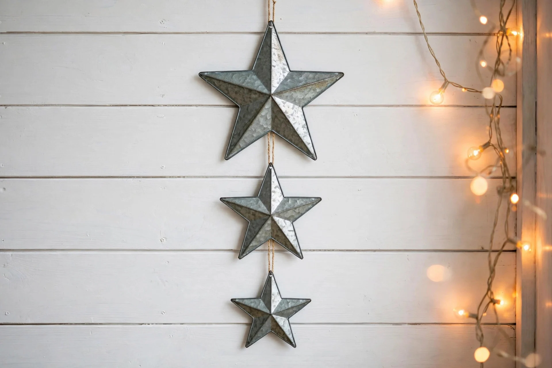 Galvanized metal stars hanging on a farmhouse wall with warm string lights