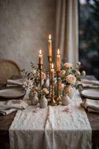 Tasteful Valentine's table setting with ivory linen runner, brass candles and blush bud vases